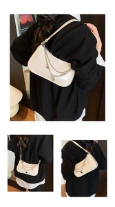 Detail of cream patent leather underarm bag with silver chain and heart charm detail