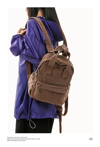 Detail of a dark brown canvas backpack featuring adjustable straps and durable metal hardware