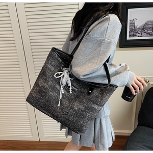 Dettaglio borsa tote grande grigia glitterata con ciondolo a fiocco e perla elegante