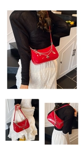 Macro view of bright red patent leather handbag with dual silver chains and heart charm