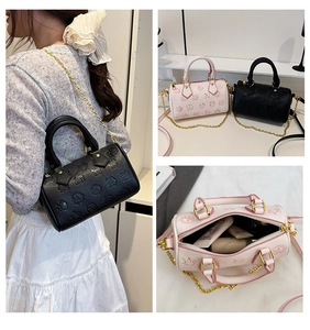 Makroansicht der Monogramm-Prägung und der geräumigen Innenseite der Mini-Boston-Bag