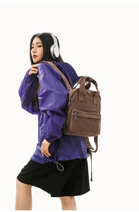 Detail view of the dark brown canvas backpack with dual top handles and zippers