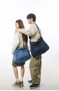 Detail of adjustable black strap and flap pocket on blue denim oversized tote bag