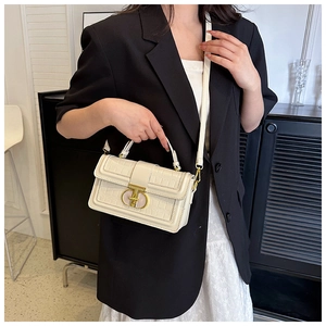 Detail of cream crocodile embossed leather handbag with gold buckle in home setting
