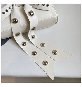 Gros plan des lanières en cuir blanc crème avec rivets métalliques argentés décoratifs