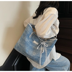 Dettaglio della borsa tote in denim blu con bordo metallico argento e ciondolo a perla