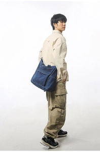 Detail showing deep blue denim tote bag with functional front flap pocket on model