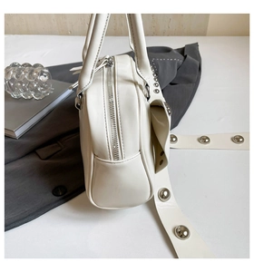Vue détaillée d'un sac à main en cuir blanc avec des rivets argentés et une fermeture éclair