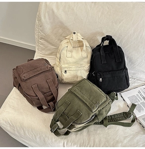 Multiple colors of washed canvas backpacks displayed on a white textured sofa