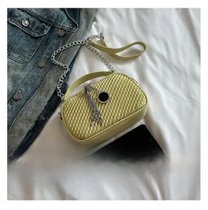 Détail du sac à bandoulière matelassé jaune pâle avec chaîne argentée et pompon