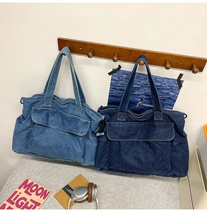 Detailed view of denim tote bag with front flap pockets and white contrast stitching
