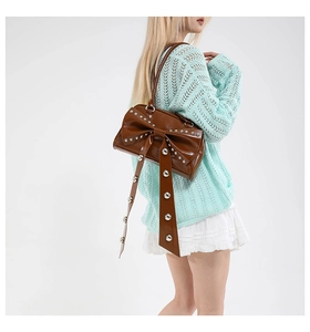 Détail du sac à bandoulière en cuir brillant marron avec grand nœud et rivets