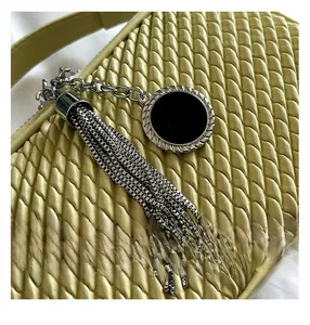 Vue détaillée de la texture tressée du sac vert clair avec pompon en chaîne métallique