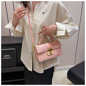 Detailed view of light pink crocodile pattern handbag with metal rotating clasp and strap