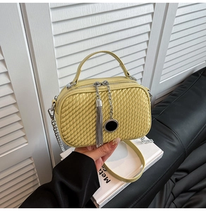 Détail du sac bandoulière jaune avec texture tressée, chaîne et gland élégant