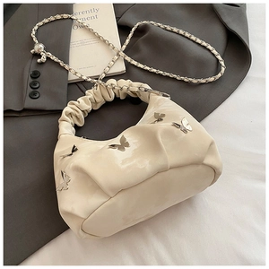 Détail du sac à main plissé crème avec papillons métalliques et bandoulière en chaîne