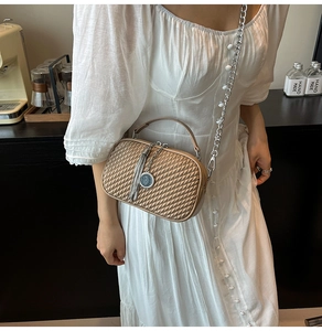 Détail du sac bandoulière champagne avec texture tressée, poignée métal et chaîne argentée