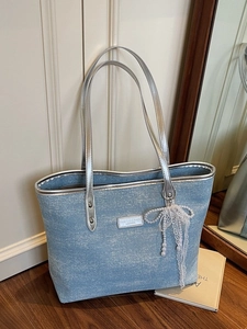 Borsa tote in denim azzurro con manici argentati e ciondolo a fiocco in pizzo e perle