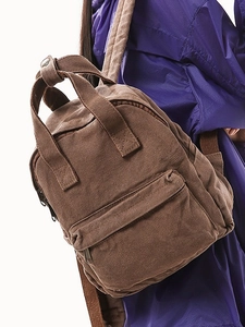 Brown canvas backpack for women with top handles and adjustable straps on model