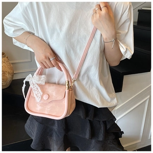 Detail view of pink mini handbag with lace bow and crossbody strap on stylish model