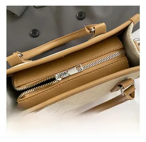 Detail of silver metal zipper and brown leather trim on canvas tote bag with stitching