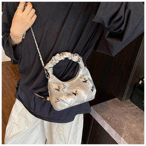 Sac à main argenté métallisé plissé avec papillons et bandoulière sur le mannequin