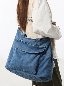 Spacious washed blue denim tote bag for women featuring a functional front flap pocket