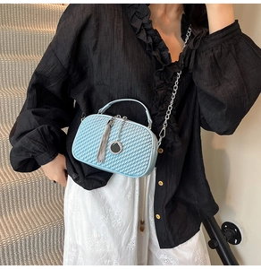 Détail du matelassage ondulé et gland argenté sur le sac bandoulière bleu clair