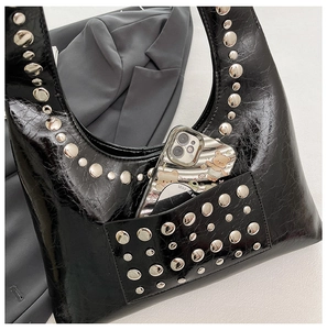 Detail einer schwarzen Lackleder-Hobo-Tasche mit silbernen Nieten und großem Innenraum