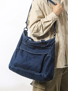 Large dark blue denim tote bag with front pocket and detachable strap on model