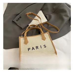 Detail of a beige woven tote bag with Paris print and adjustable leather strap
