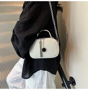 Détail du sac bandoulière blanc matelassé avec chaîne argentée et pendentif à pompon