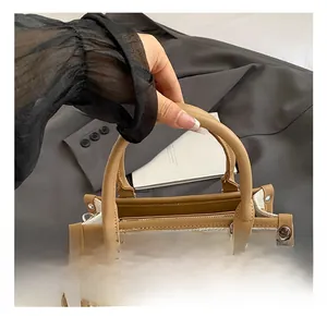 Detail of beige fabric tote with brown leather handles and decorative metal rivets