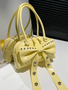 Sac à main en cuir verni jaune pâle avec nœud à rivets et double poignée