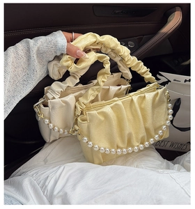 Détail des sacs nuages plissés en jaune et crème avec chaînes perlées dans une voiture