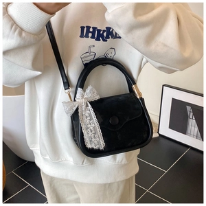 Detail of a black velvet saddle bag featuring a white lace bow and leather strap