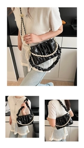Détail du sac nuage noir brillant avec chaîne de perles et texture plissée élégante
