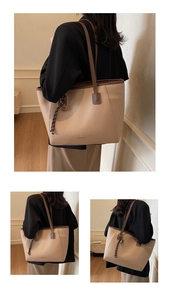 Detail of a large beige PU leather tote bag featuring brown straps and a woven pendant