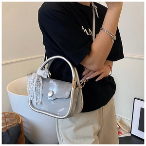 Close-up of silver crescent handbag with white lace bow and metallic finish