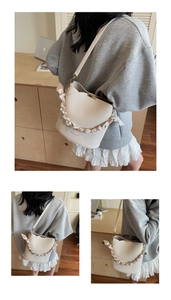 Detail of cream bucket bag with litchi texture and silk scarf wrapped chain strap