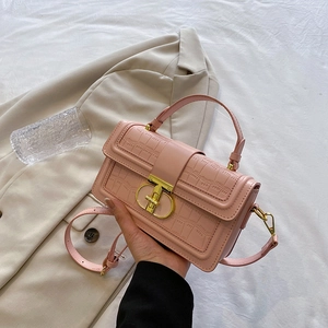 Pink faux leather handbag with crocodile texture and gold buckle on a neutral background