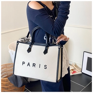 Dettaglio della borsa tote Paris in tela bianca con finiture in pelle nera e tracolla rimovibile