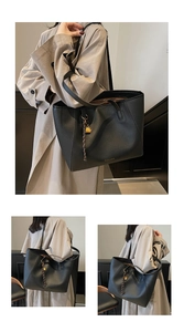 Detail of black large tote bag with lychee grain texture and golden padlock charm