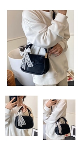 Detail of black saddle bag with white lace bow accent and matte leather finish