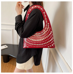 Detail der roten Hobo-Tasche aus Kunstleder mit silbernen Nieten an einem Modell