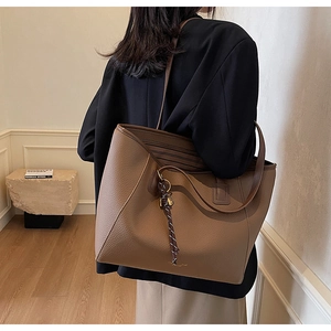 Brown lychee texture PU tote bag with long straps shown in a minimalist interior setting