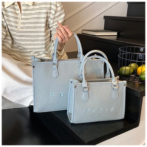 Dettaglio di borse tote intrecciate azzurre con ricamo PARIS in dimensioni grandi e piccole