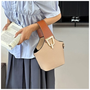 Dettaglio della borsa a secchiello in pelle beige con manico marrone e fibbia dorata