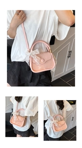 Detailed view of pink crossbody bag featuring white lace bow and adjustable shoulder strap