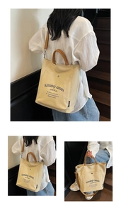 Detail view of canvas tote bag with brown handles and adjustable shoulder strap